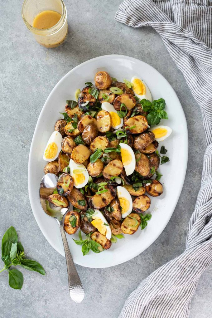 grilled potato salad on serving plate with fresh basil