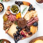 Cheese board filled with a variety of meats, cheeses, fruit and crackers