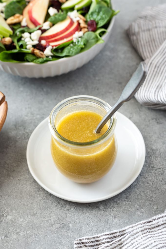 Apple cider vinegar salad dressing in a jar with spoon and salad in background