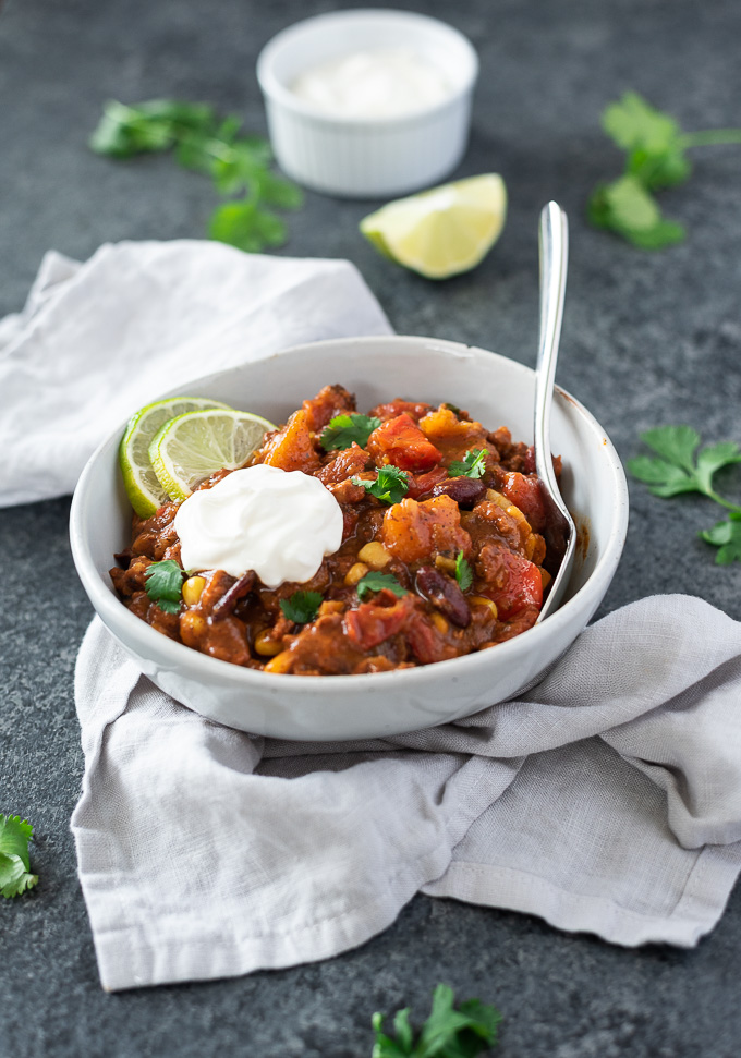 Butternut squash chili in a bowl with sour cream a spoon