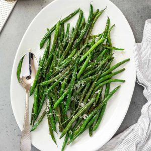 platter of roasted green beans with a spoon and linen