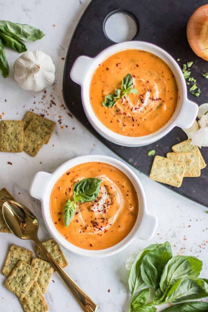 Creamy tomato basil soup in bowls with basil on top