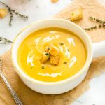 Butternut squash soup in a white bowl with croutons on top