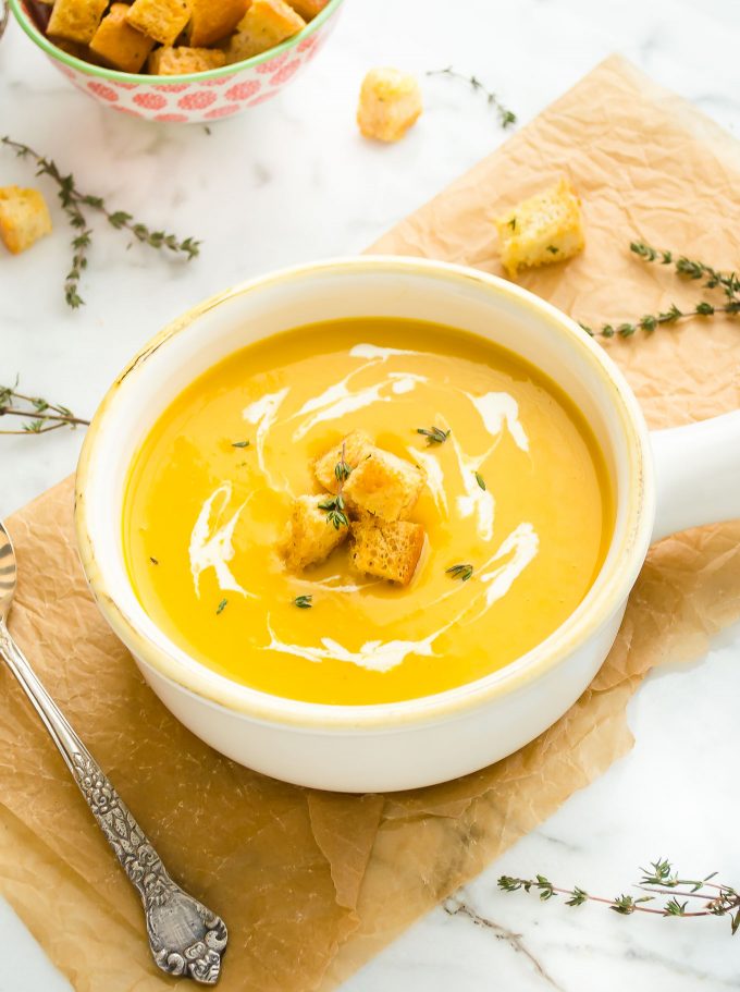 Butternut squash soup in a white bowl with croutons on top