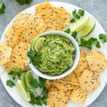 Homemade guacamole on platter with chips and lime