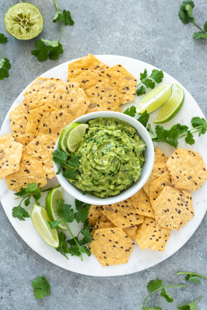 Homemade guacamole on platter with chips and lime