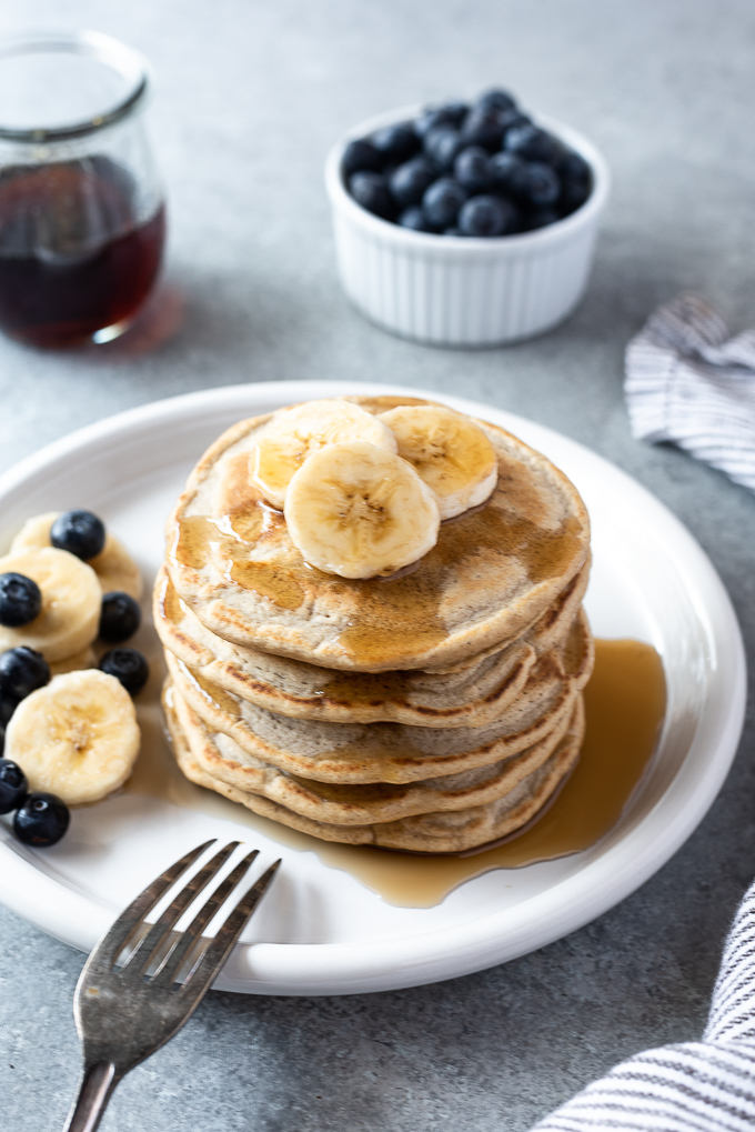 Fluffy oat flour pancakes on a plate with bananas and blueberries