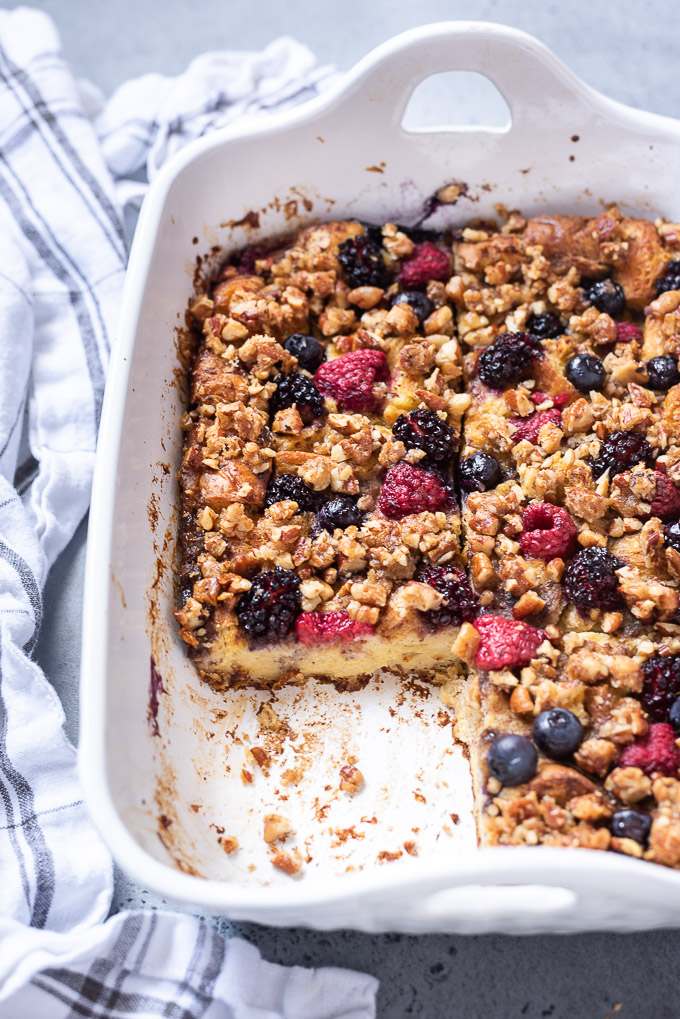 Sliced french toast casserole in a baking dish with berries on top