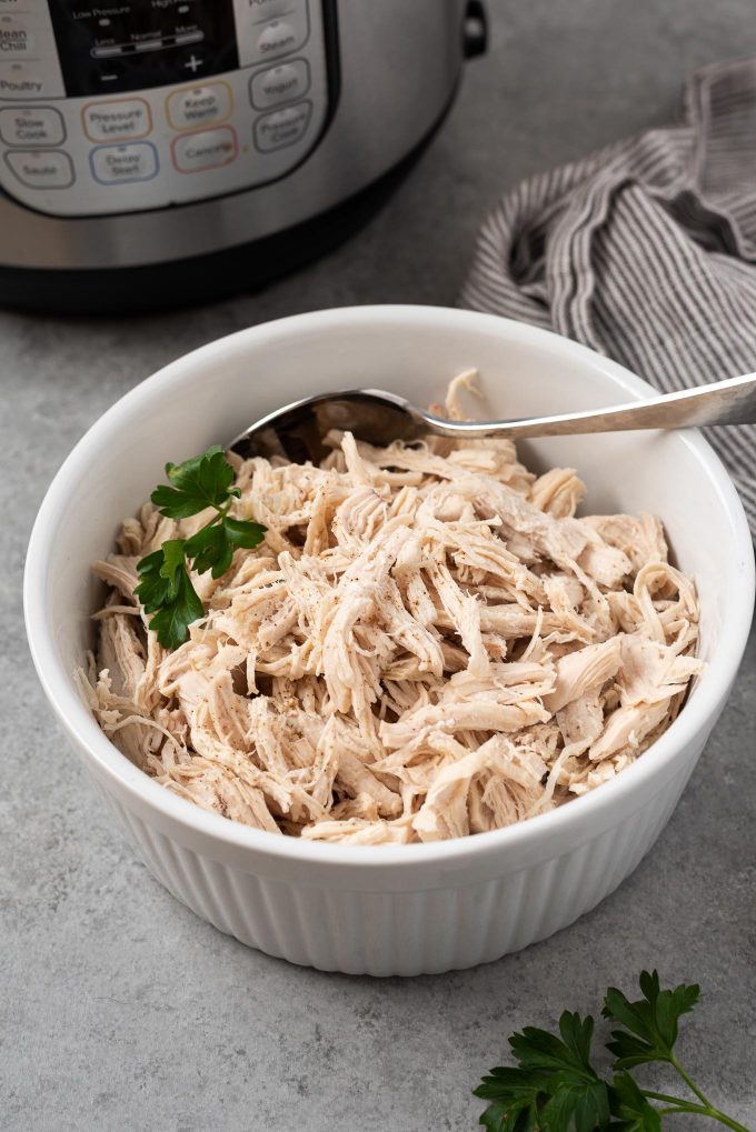 Instant Pot shredded chicken in a white dish with parsley