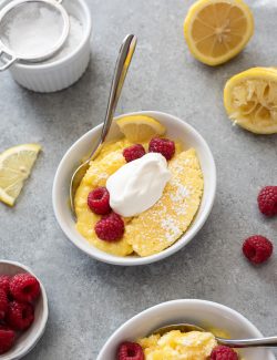 Serving of lemon pudding cake in a bowl with whipped cream and berries