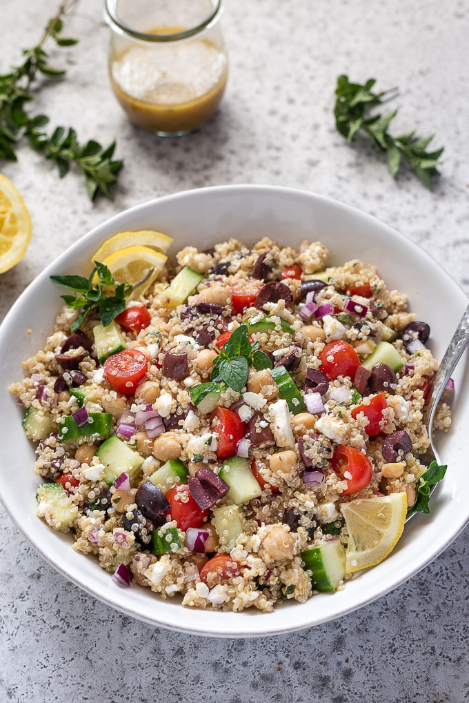 Greek quinoa salad in a bowl with spoon buried inside