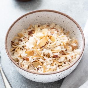 Bowl of almond rice pilaf with fork and linen