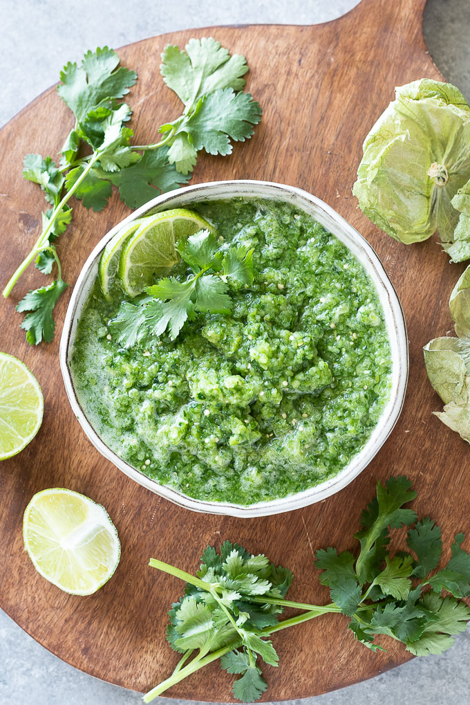 White bowl filled with green salsa with lime and cilantro on top