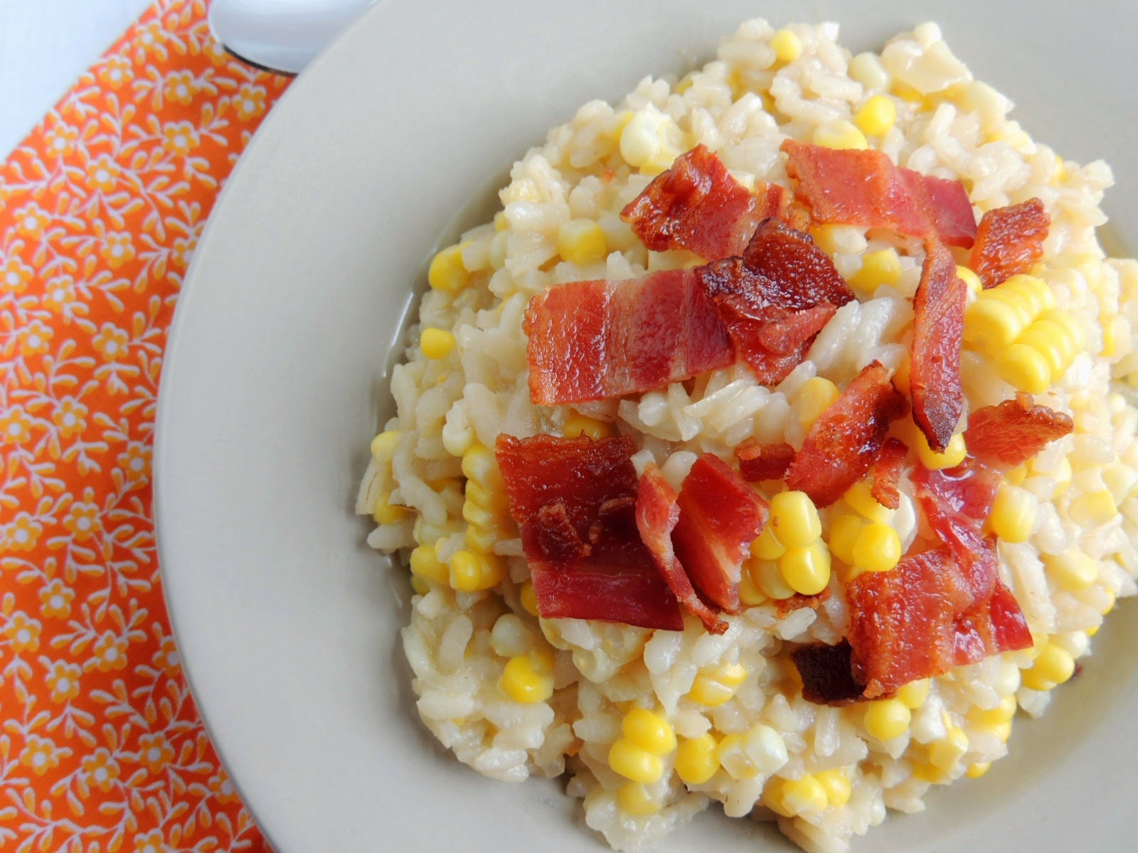 Overhead view of bacon and corn risotto in a white dish.
