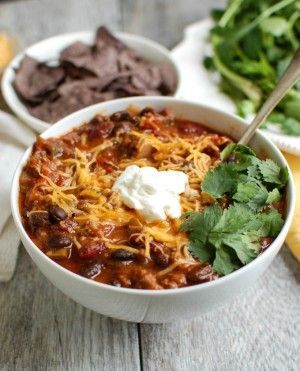 A large bowl of beef poblano chili topped with sour cream, cheese, and cilantro.