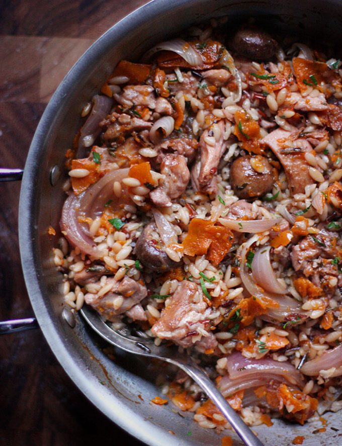 Chicken and wild rice in a skillet. A spoon rests on the edge of the skillet.