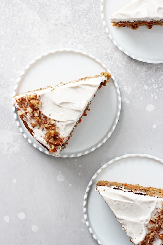 Two slices of dairy free carrot cake on white plates.