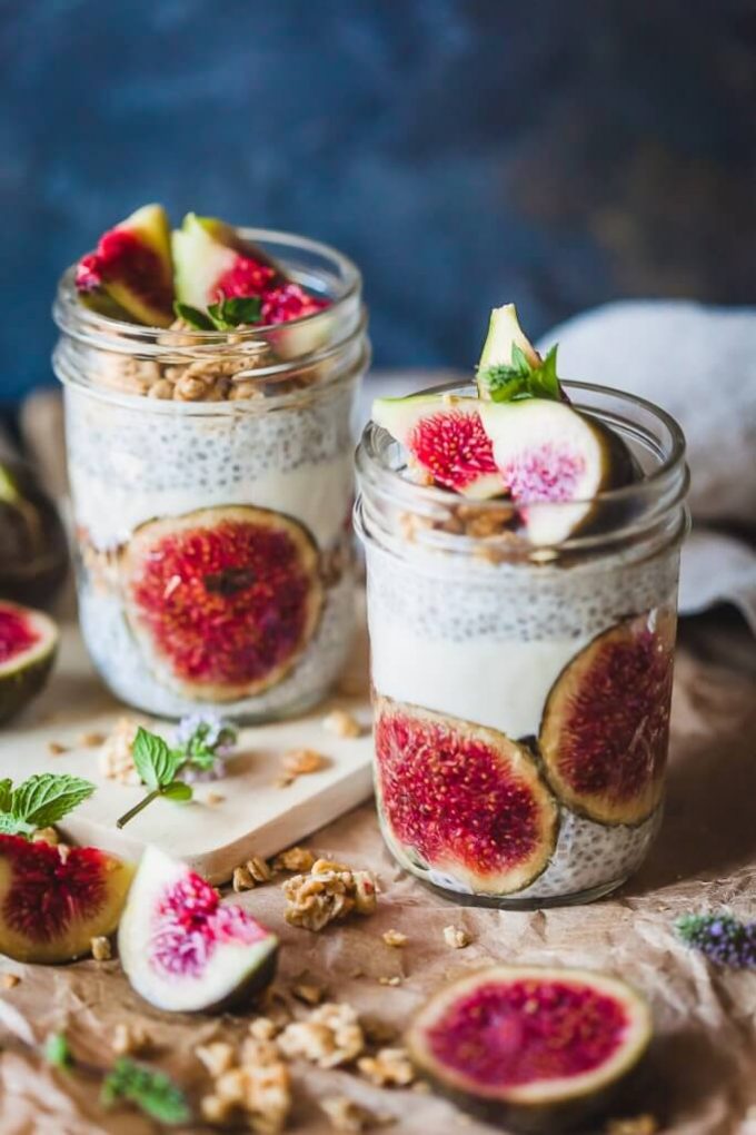 Two mason jars filled with fig chia pudding. Fig halves are scattered around them,