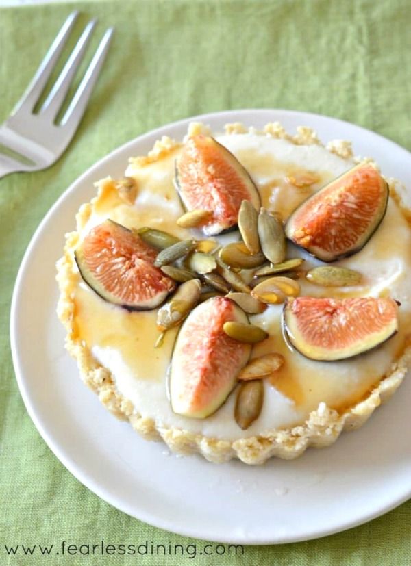 A fig tart on a white plate next to a fork.