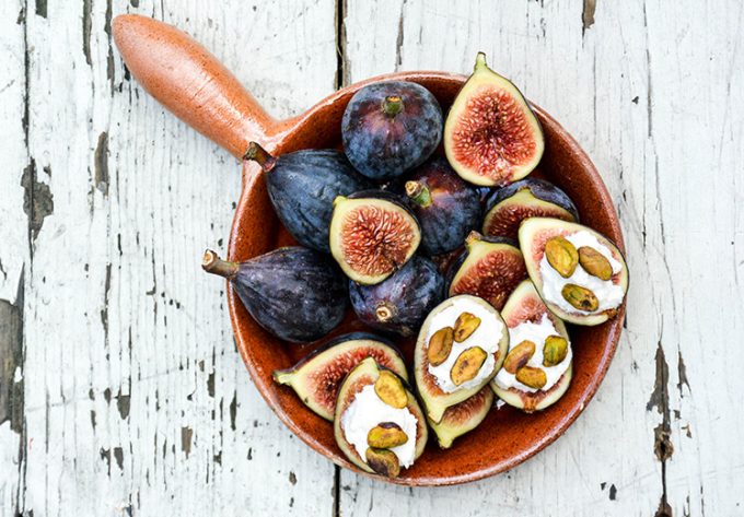 Overhead view of fresh figs with ricotta and pistachios in a dish.