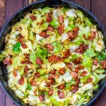 Overhead view of fried cabbage with bacon in a cast iron skillet.