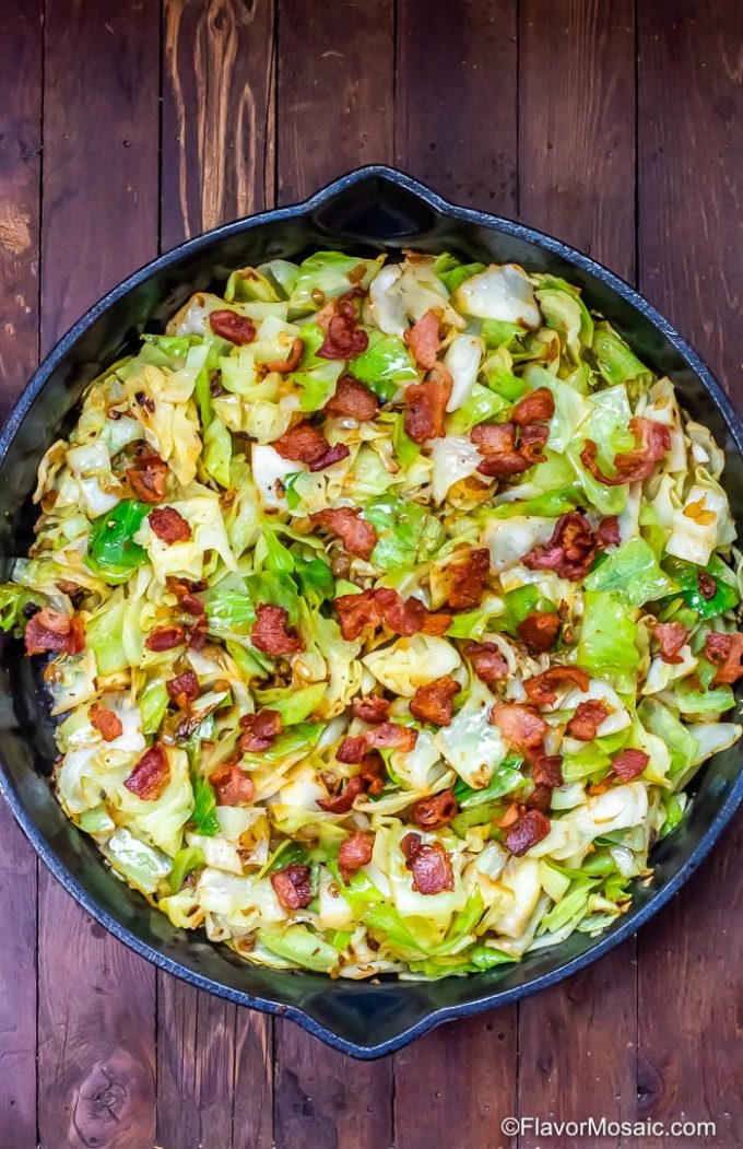 Overhead view of fried cabbage with bacon in a cast iron skillet.