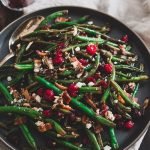 Green beans with cranberries on a dark gray plate.