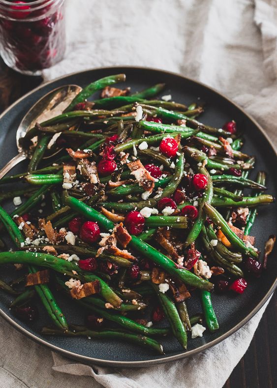 Green beans with cranberries on a dark gray plate.