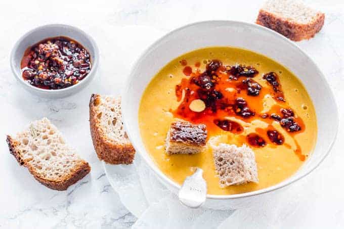 A bowl of sweet potato carrot soup with hunks of bread.