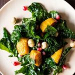 Overhead view of a kale salad with kabocha squash and pomegranate aerils.