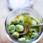 Spoon in a jar of marinated fava beans