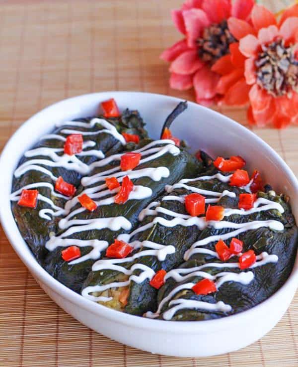 Four chiles rellenos in a white baking dish.