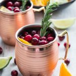 Two cranberry orange moscow mules in copper mugs.