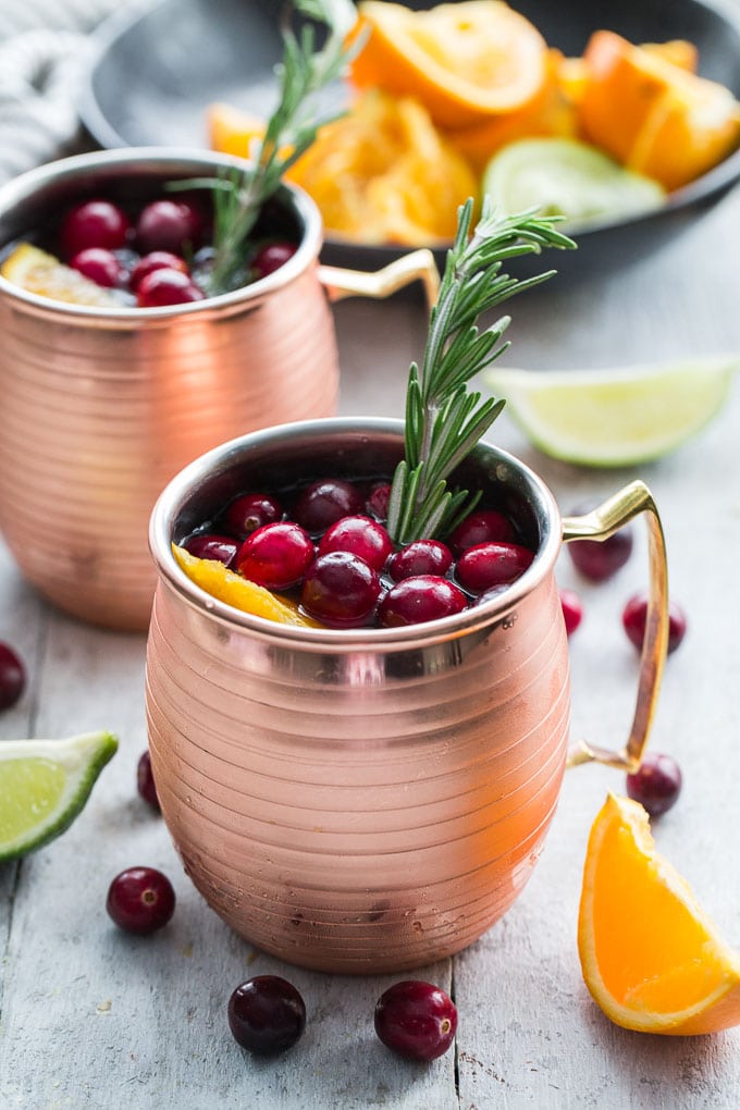Two cranberry orange moscow mules in copper mugs.