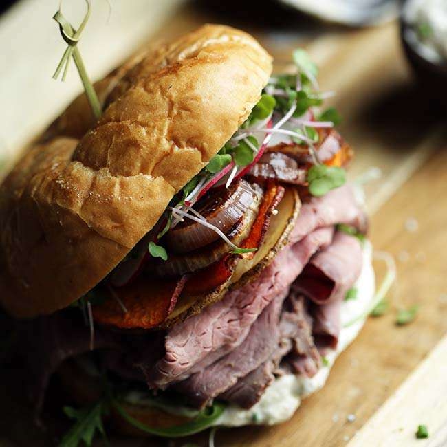 A loaded roast beef sandwich with a toothpick in the top.