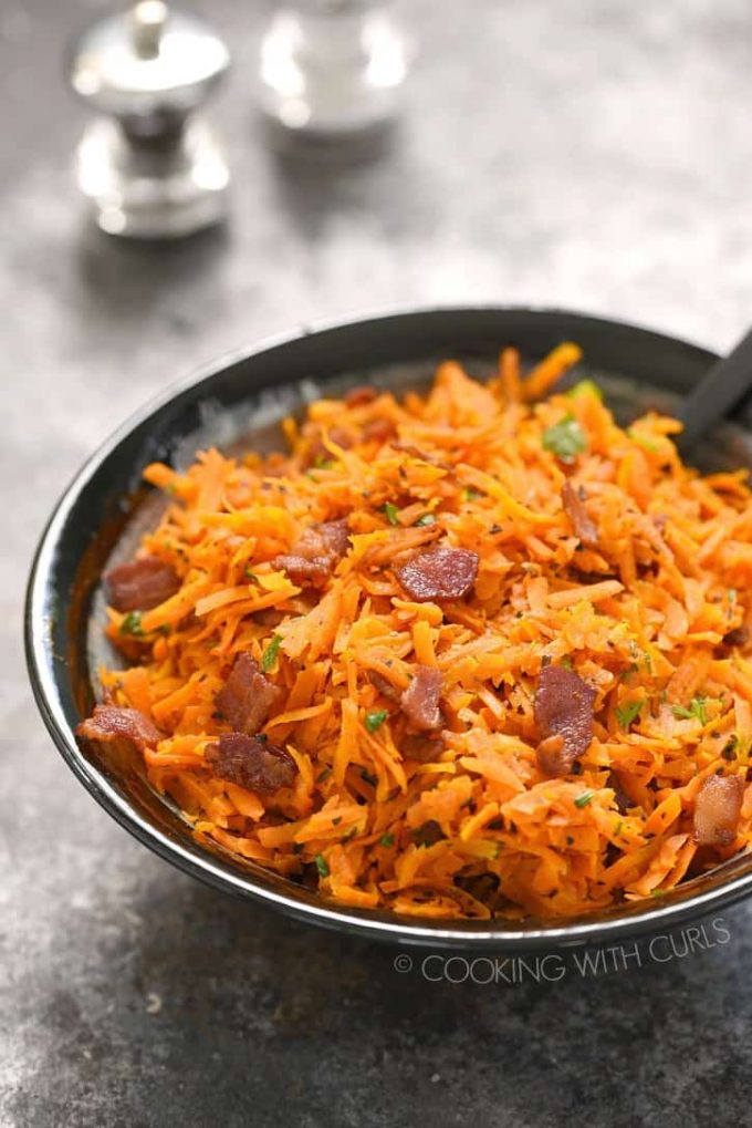 A gray dish of shredded carrots with bacon.