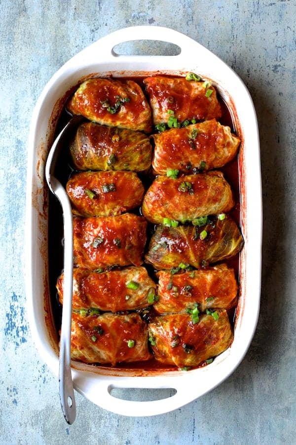 Overhead view of Asian pork cabbage rolls in a white baking dish.