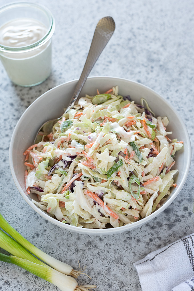 Coleslaw in a bowl with a spoon buried inside