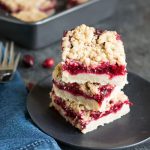 A stack of three cranberry shortbread bars on a dark gray plate.