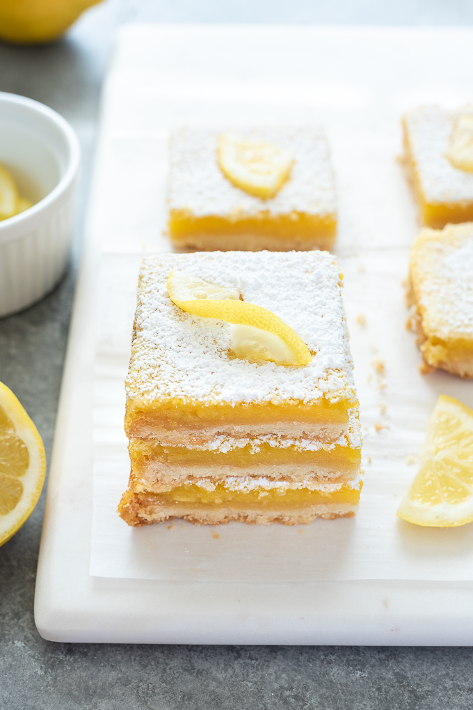 Stack of lemon bars on a platter with lemon slice on top