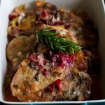 A blue baking dish of slow cooker pork chops with cranberries.