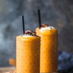 Two turmeric persimmon smoothies in glasses with straws.