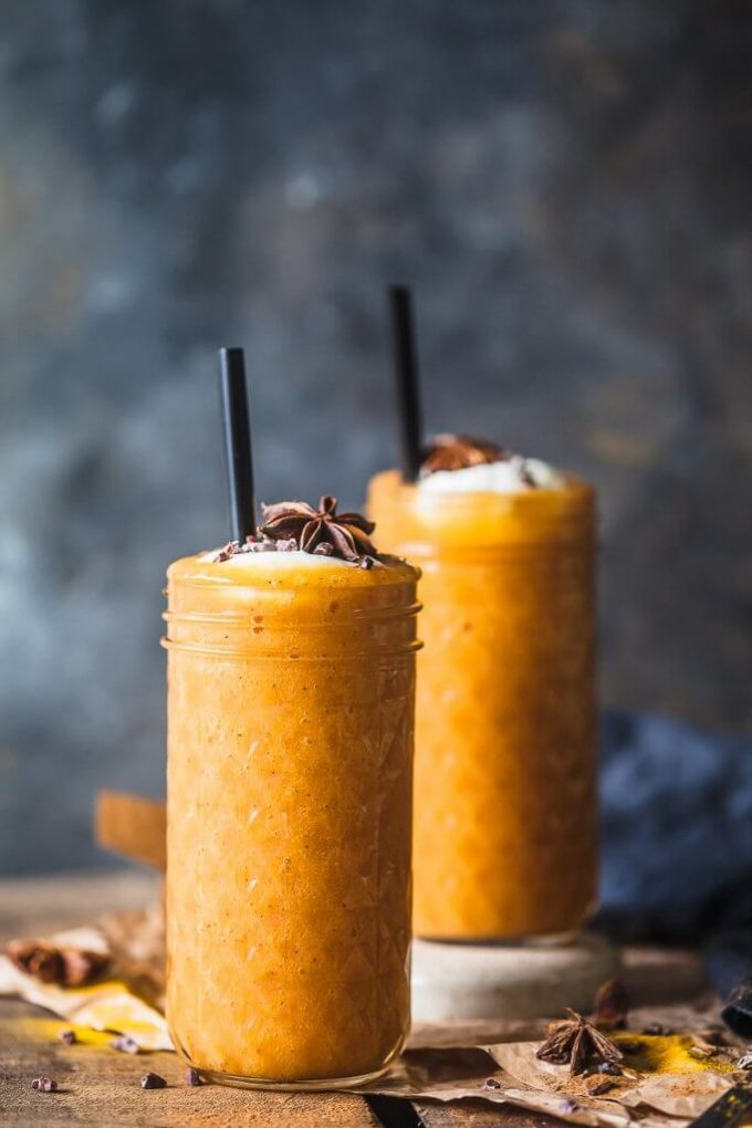 Two turmeric persimmon smoothies in glasses with straws.