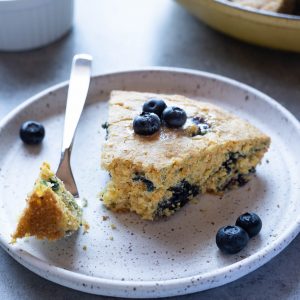 Slice of blueberry cornbread on plate with a fork