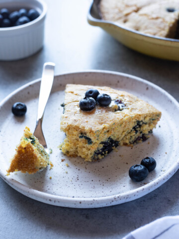 Slice of blueberry cornbread on plate with a fork