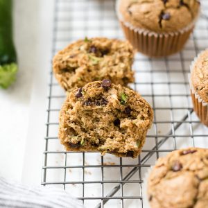 Oat flour zucchini chocolate chips muffins on a wire rack.