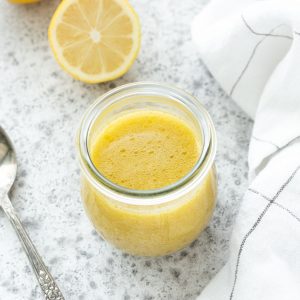 Lemon vinaigrette in a jar with a spoon nearby