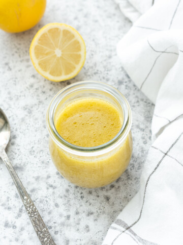 Lemon vinaigrette in a jar with a spoon nearby