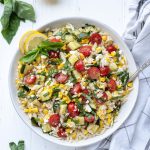 Lemon orzo pasta salad in a white bowl with basil on top