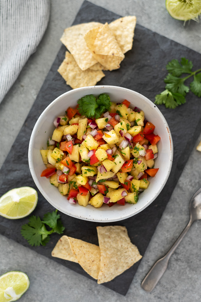 Pineapple salsa with chips, lime wedges and cilantro